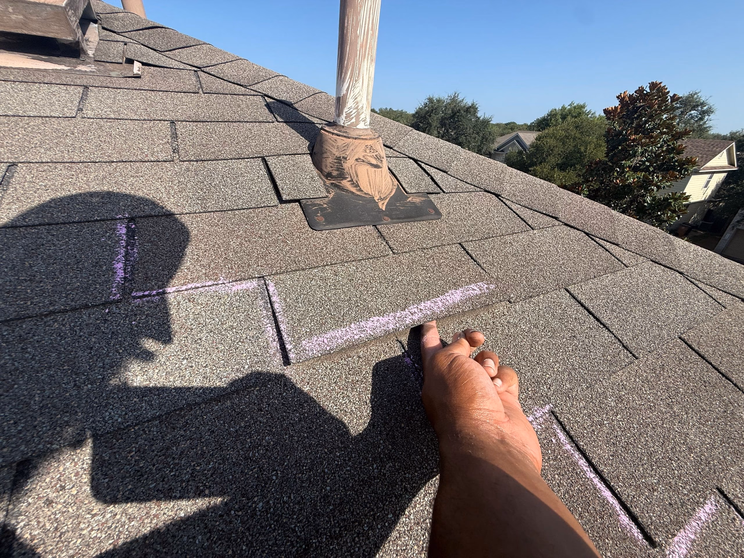 Chalk marks documenting wind damaged shingles for an insurance claim in Austin, TX