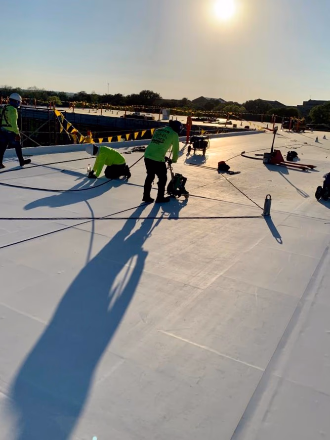 Austin Roofing Company crew welding seams on a white TPO membrane during a commercial flat roof installation in Austin, TX