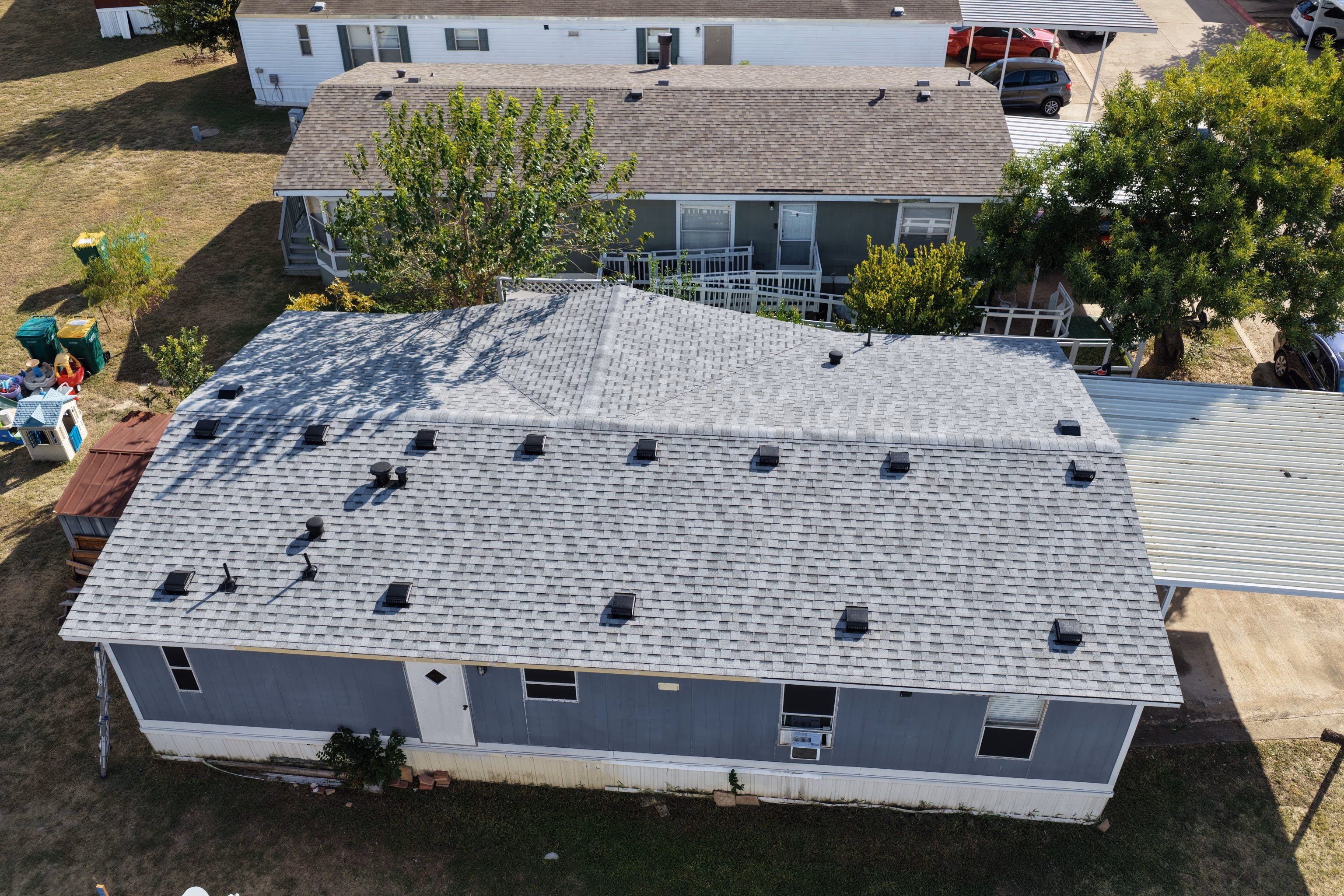 Aerial view of a completed shingle roof replacement overlooking the driveway in Austin, TX