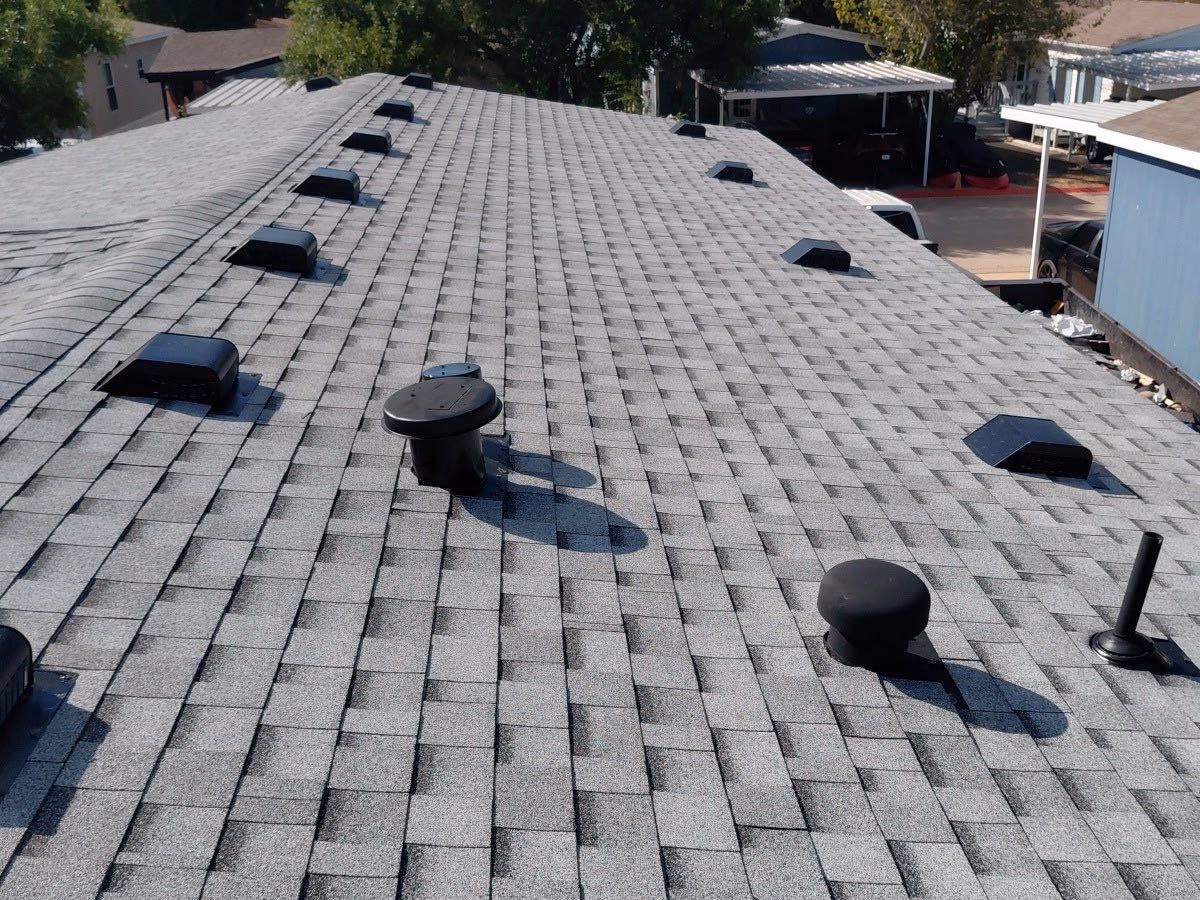 Close-up aerial view of a new shingle roof with vents installed in Austin, TX