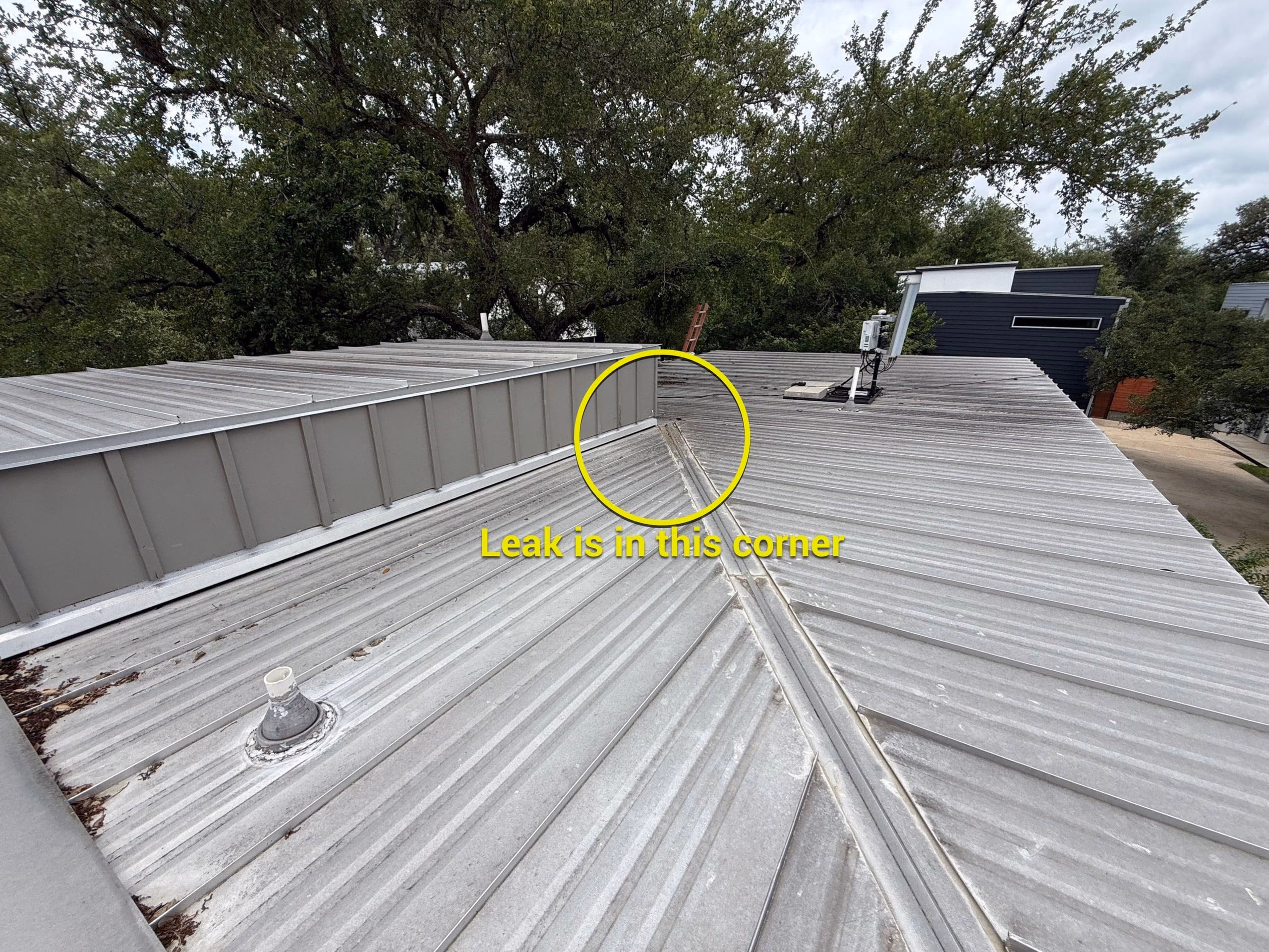 Metal roof inspection photo with a yellow circle marking the valley corner where a leak was found