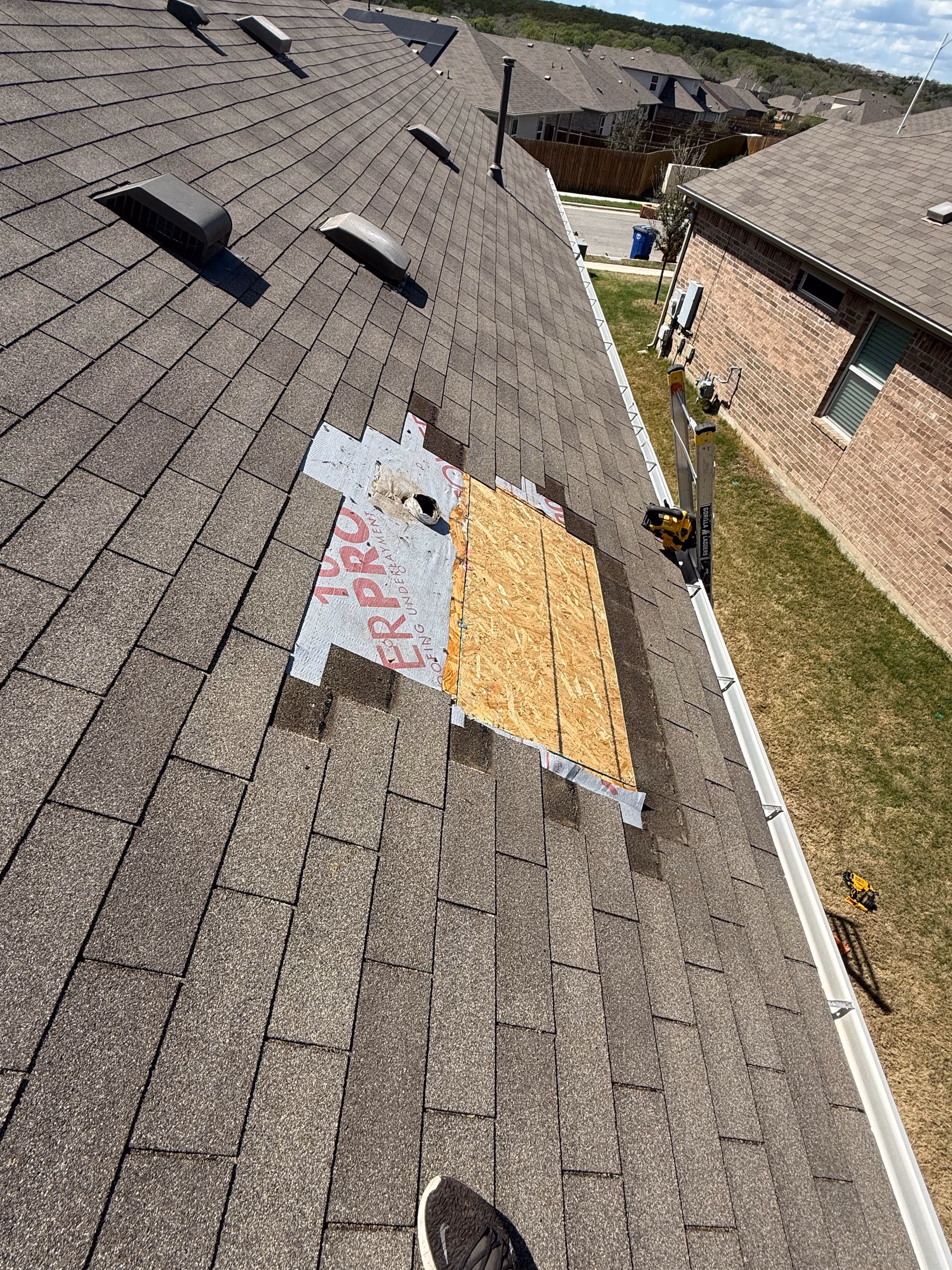 New plywood decking patch and synthetic underlayment installed on a brown shingle roof during an Austin roof repair