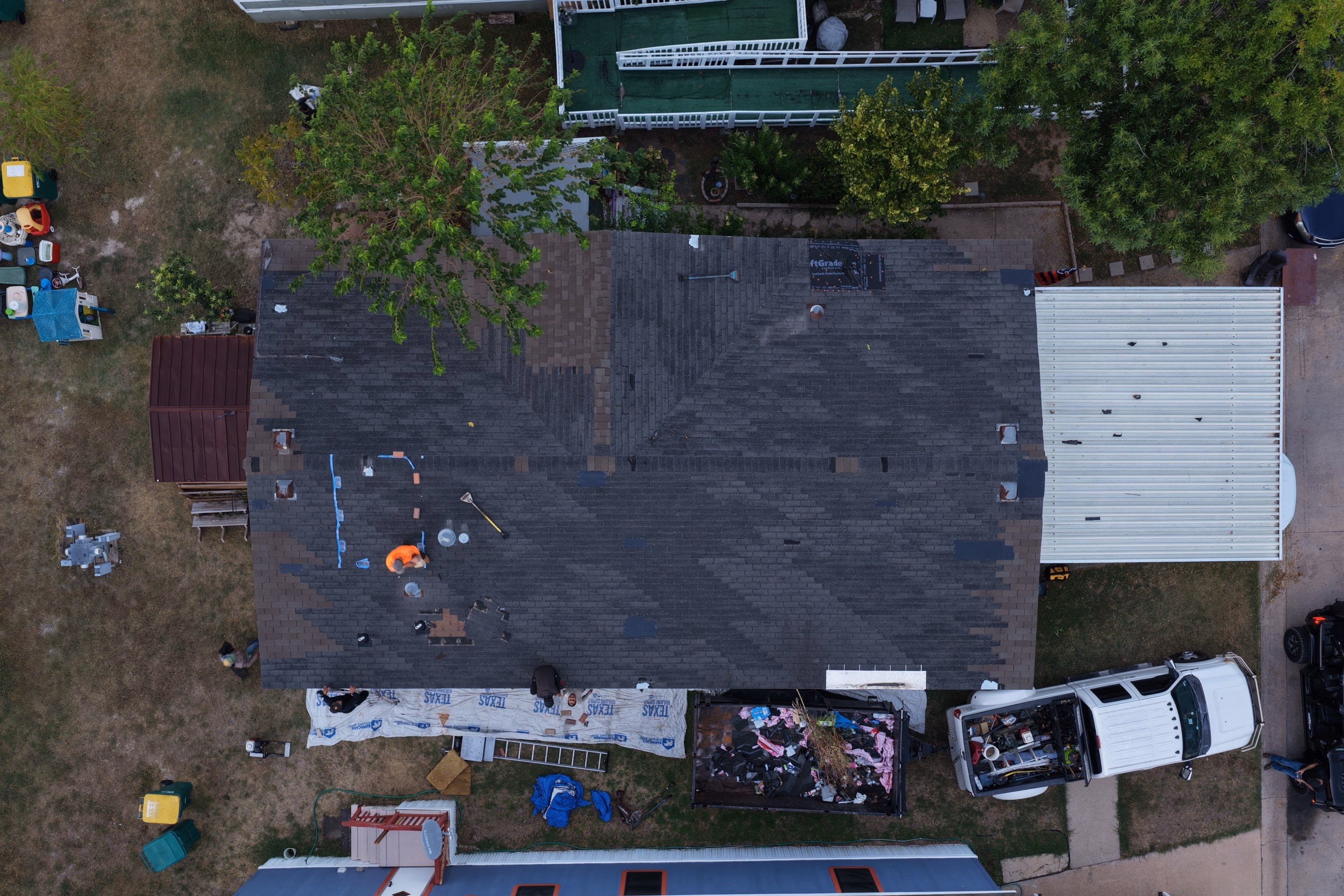 Roofer inspecting and marking an aging shingle roof before tear-off begins during a roof replacement in Austin, TX