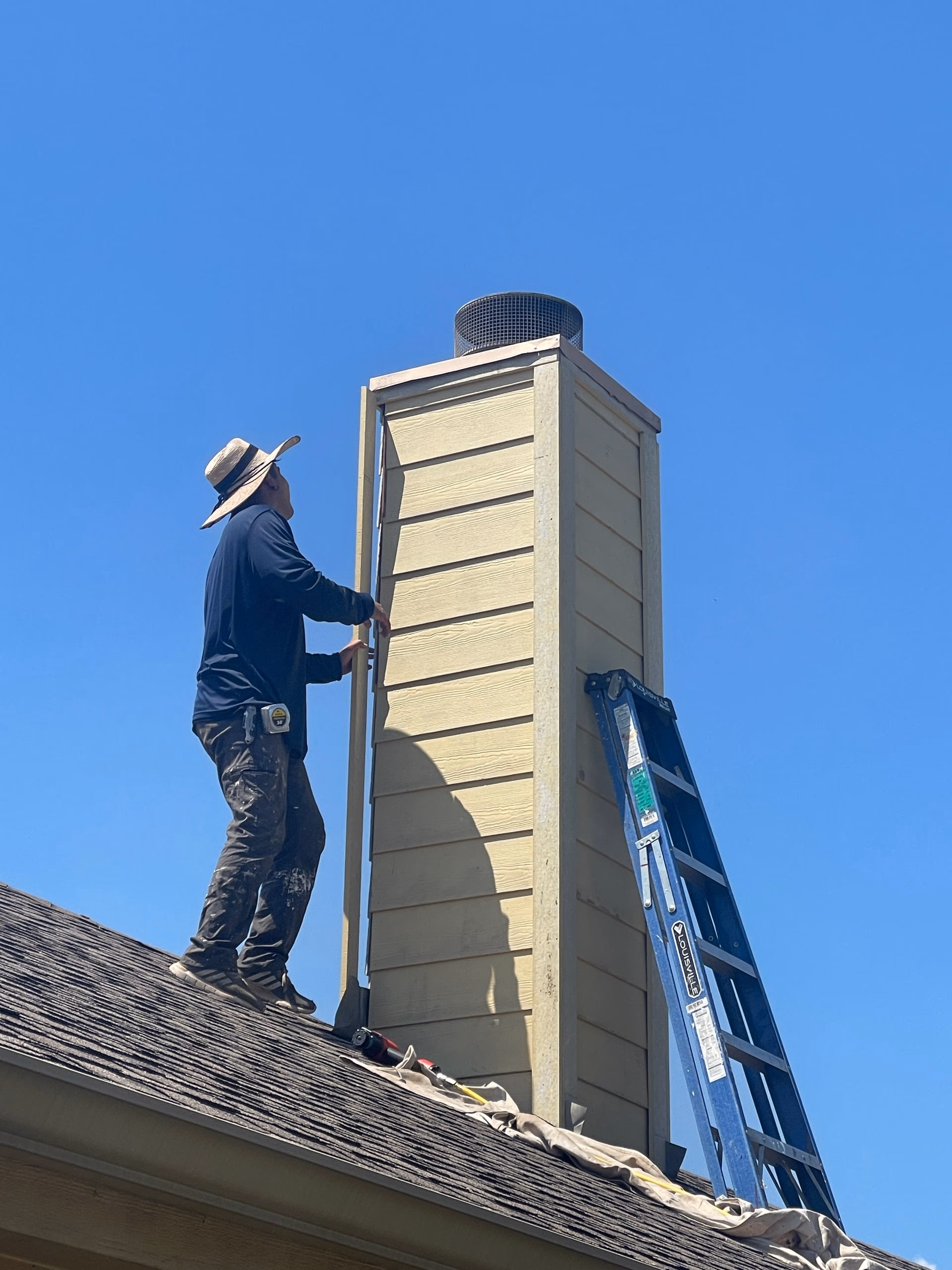 Austin Roofing Company inspector checking the chimney chase and roofline of an asphalt shingle roof during an Austin roof inspection
