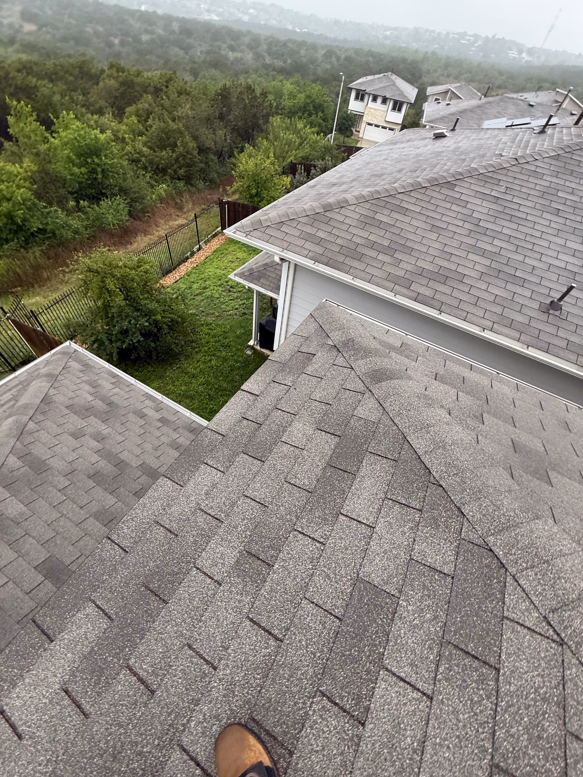 View across the planes of a gray shingle roof from the rooftop during a roof inspection in Austin, TX