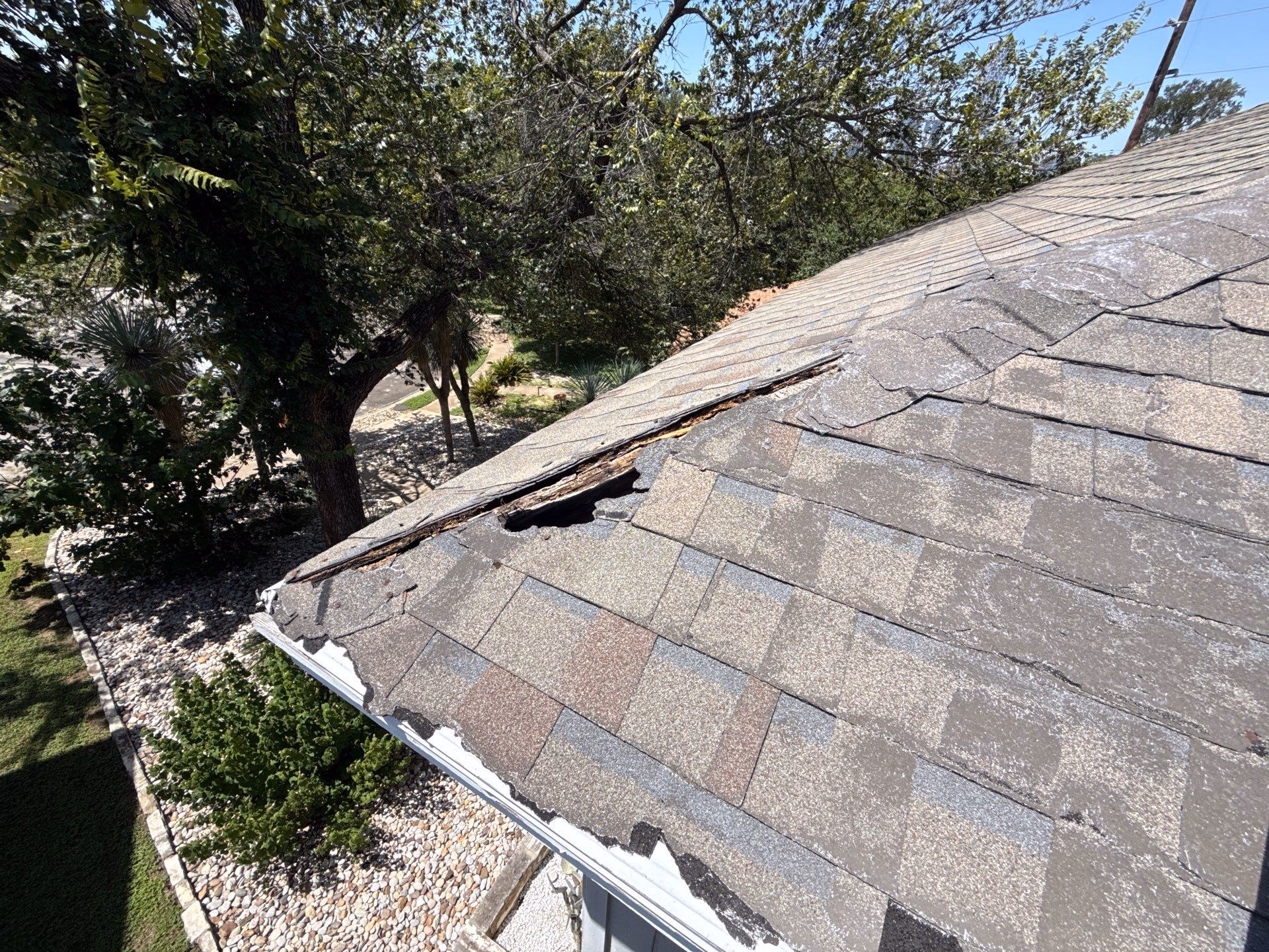 Rotted hole in a roof eave with collapsed decking and broken shingles found during a repair visit in Austin, TX
