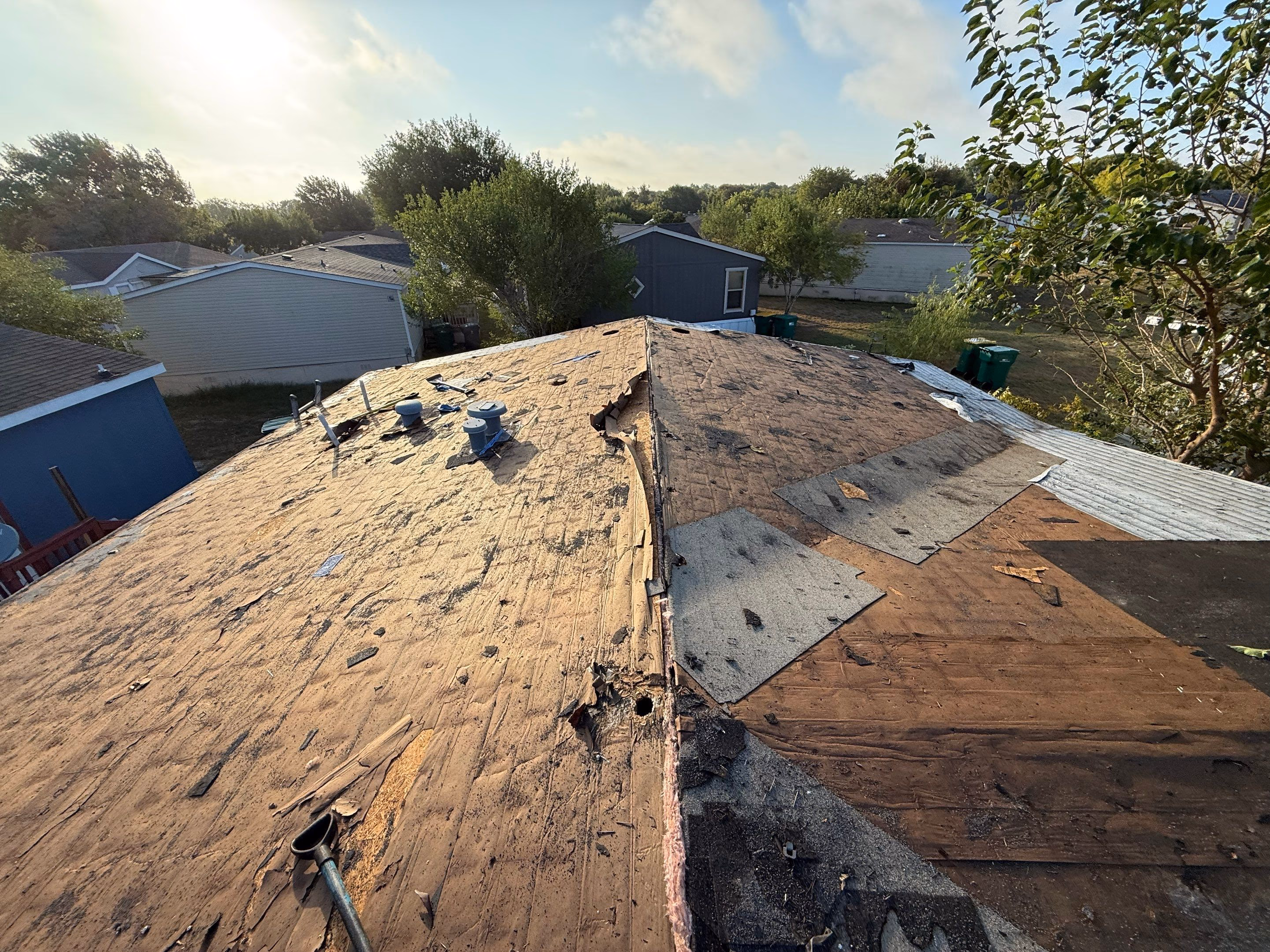 Old roof deck and damaged sheathing revealed after shingle tear-off during a roof replacement in Austin, TX