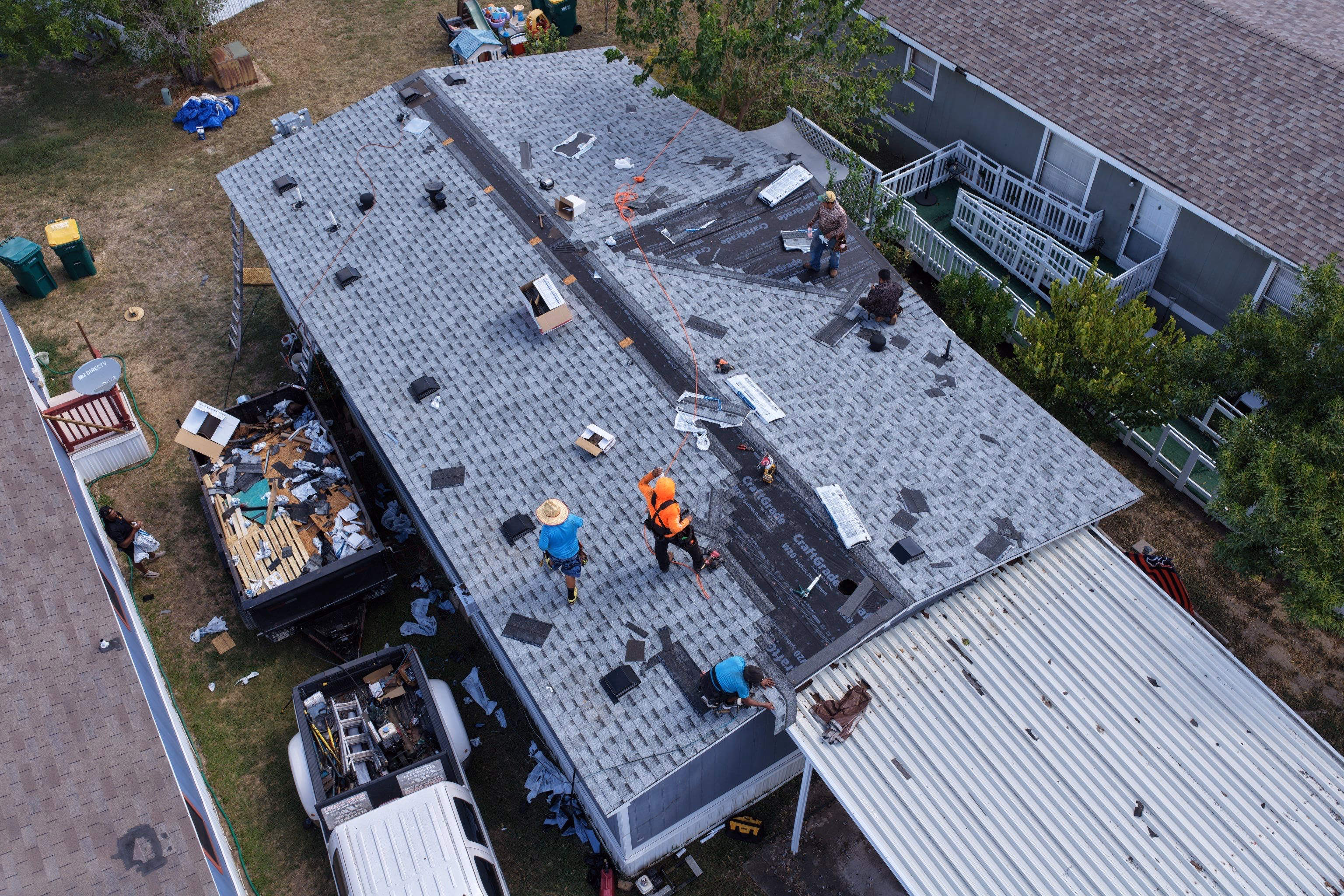 Roofers installing new shingles over synthetic underlayment, roof nearly complete, during a replacement in Austin, TX