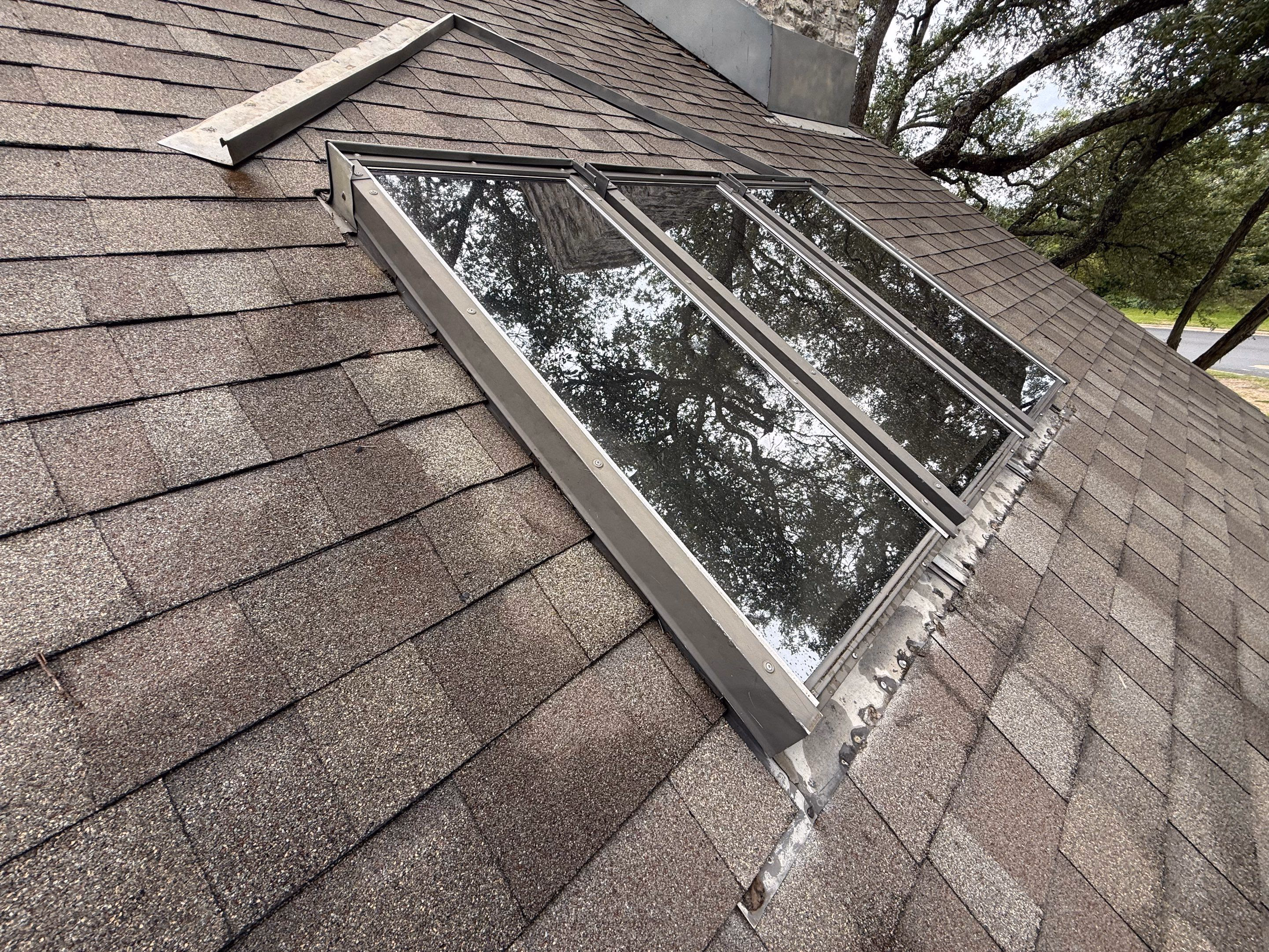 Before skylight repair in Austin, TX: aging skylight with failed flashing and deteriorated seals on an asphalt shingle roof
