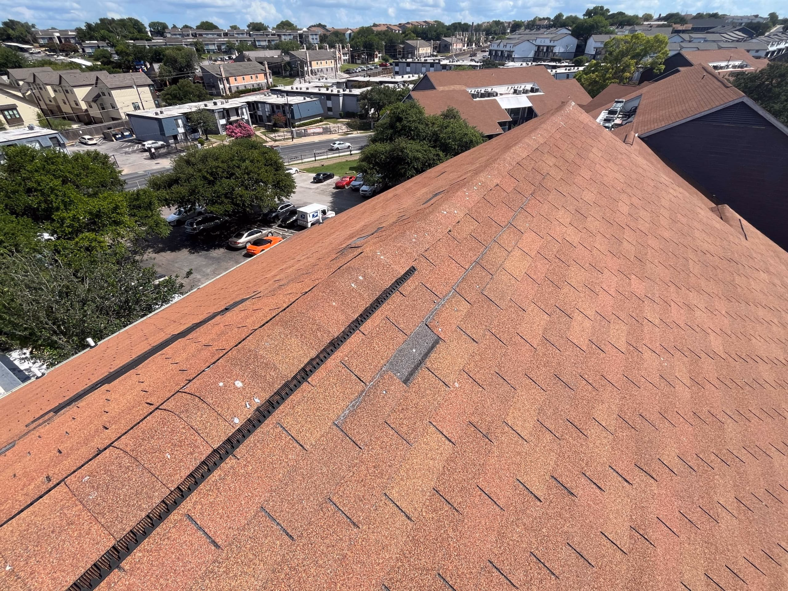 Slipped and displaced shingles mid slope on a red three tab roof after storm winds in Austin, TX