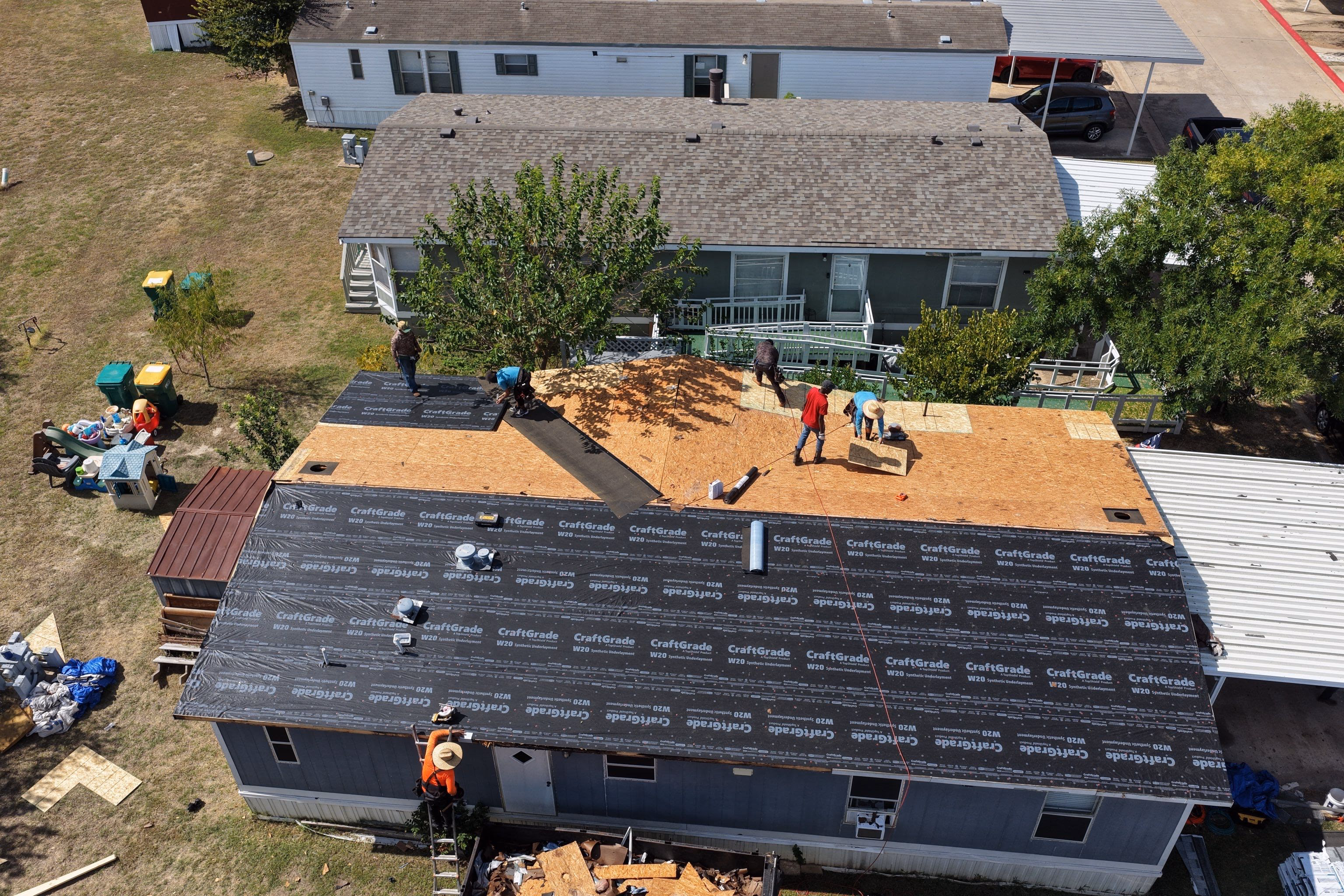 Aerial view of a crew installing synthetic underlayment across a roof deck during a replacement in Austin, TX